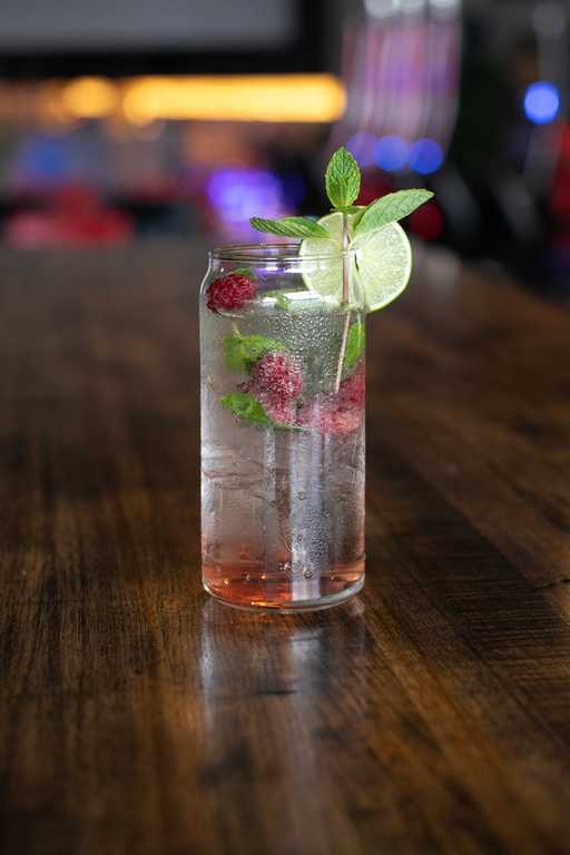 "Sweet Pepper Spritzer" cocktail at Jive Lounge, a refreshing sparkling drink infused with raspberries, mint, and lime, served over ice in a tall glass.